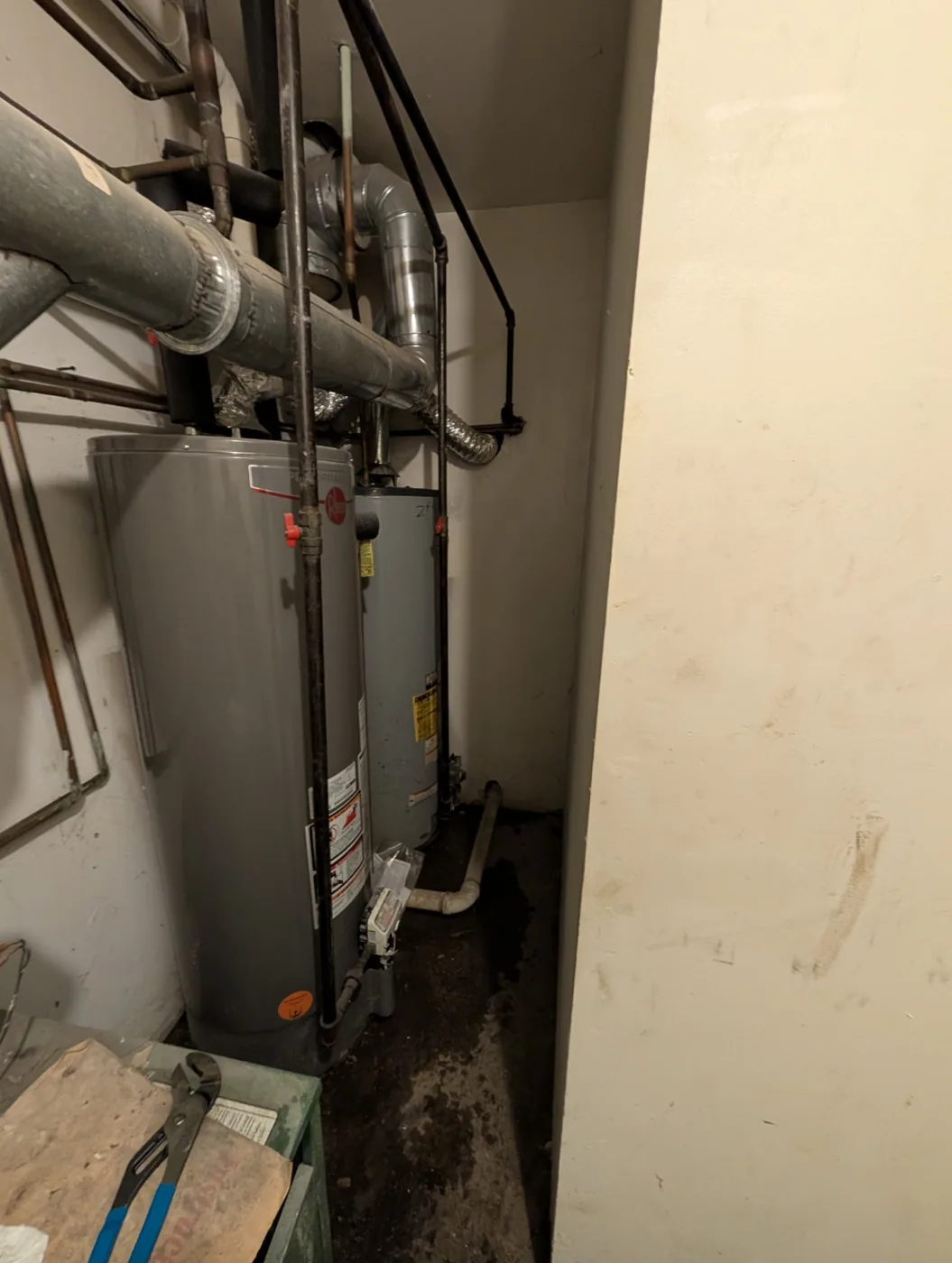 Two failed Rheem water heaters with water leaking onto the floor